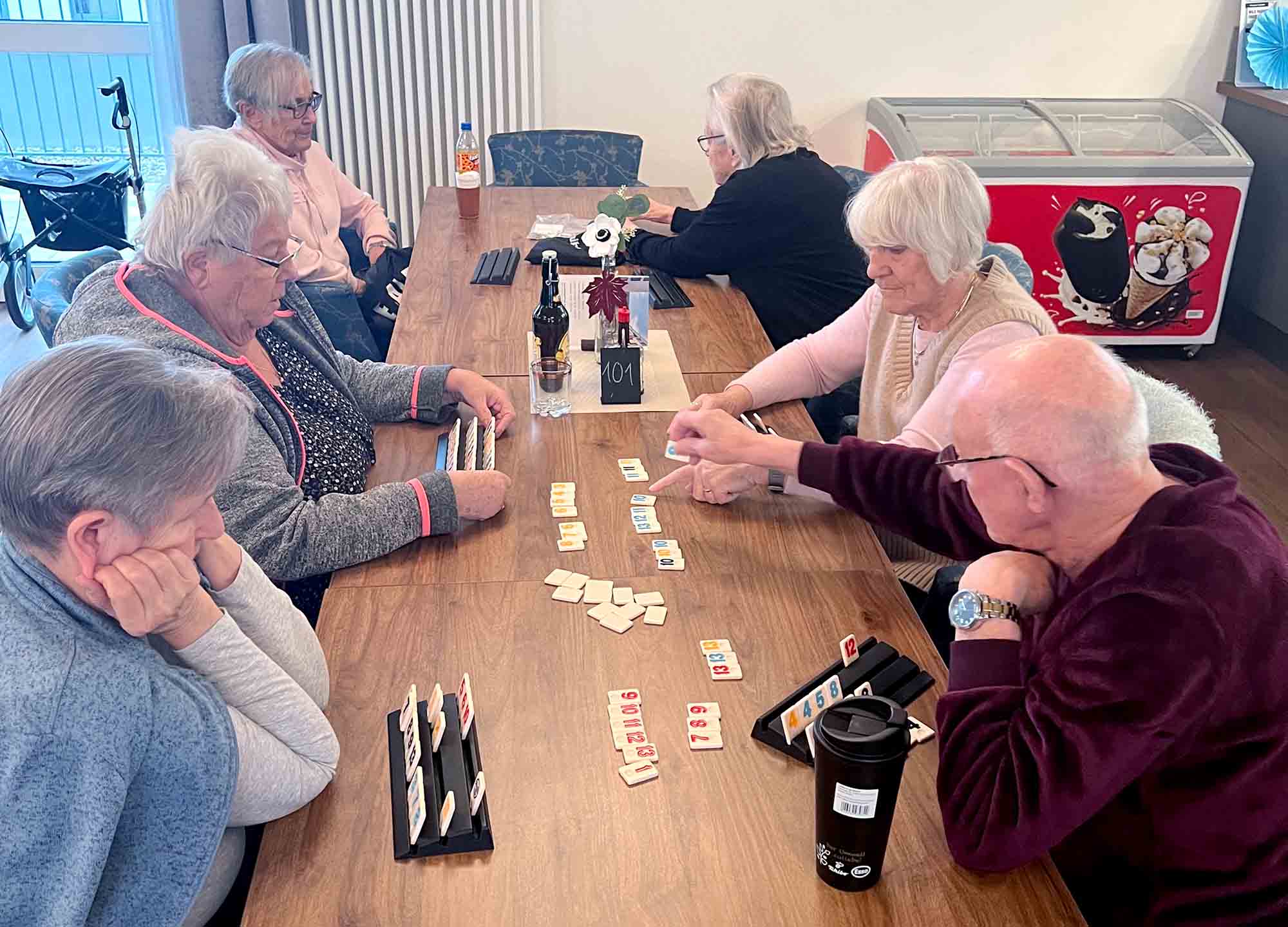 Sechs Senioren sitzen an grossem Tisch bei Gemeinschaftsspielen